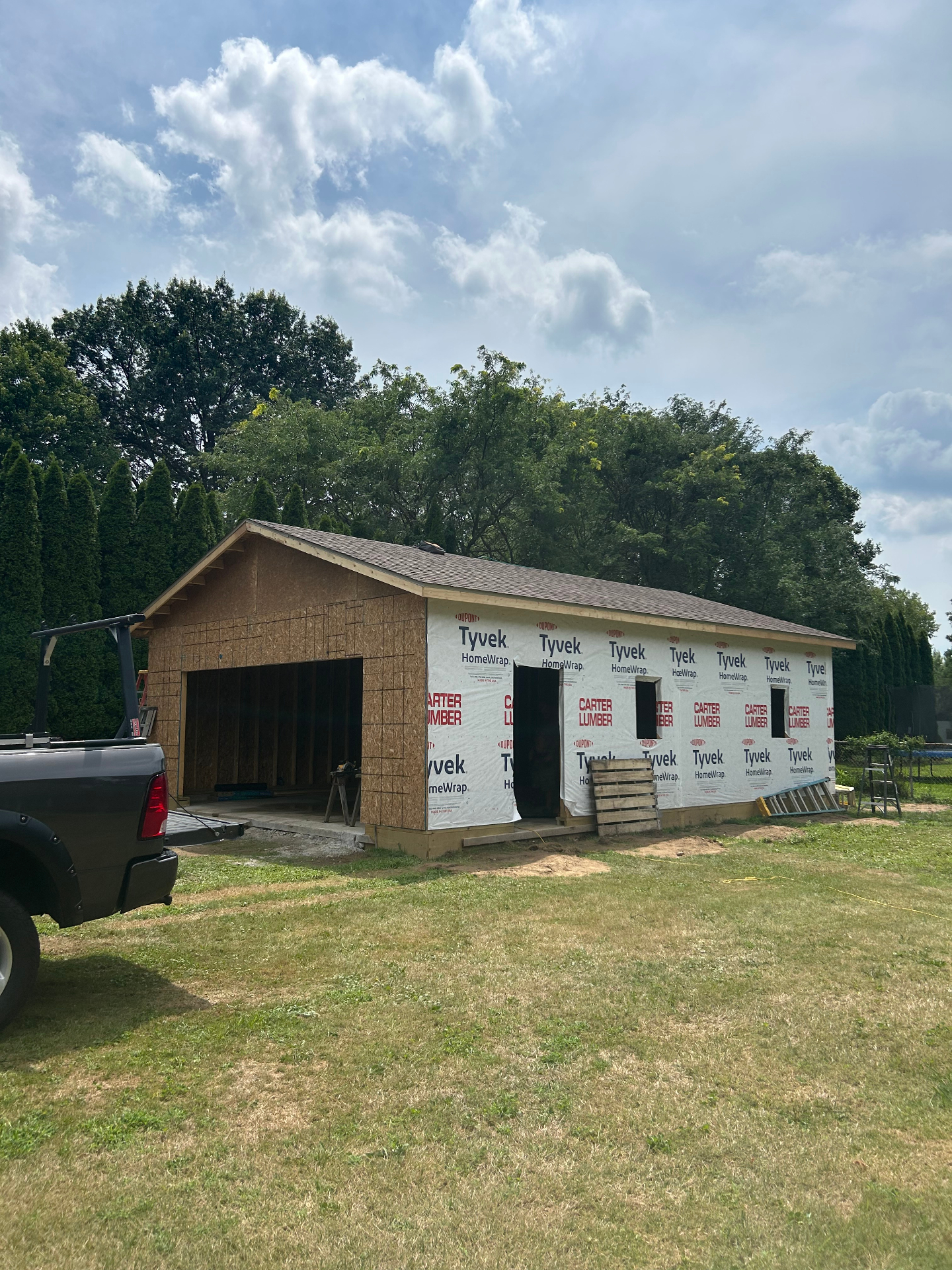 Custom garage build nearing completion with fresh roofing and wall sheathing