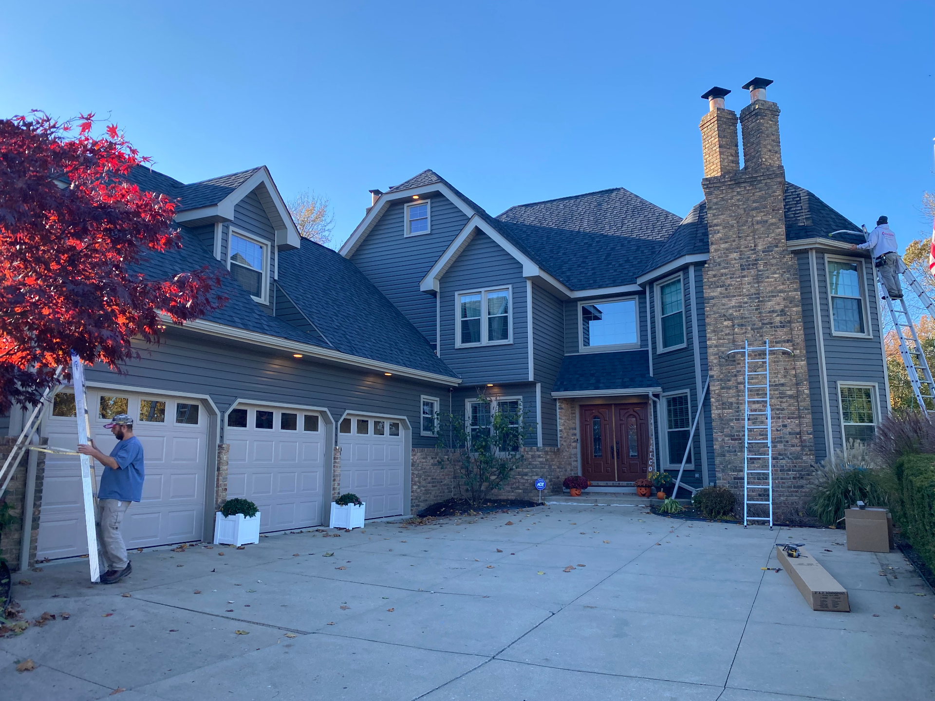 Large two-story home with dark siding and new architectural shingle roof during exterior upgrade
