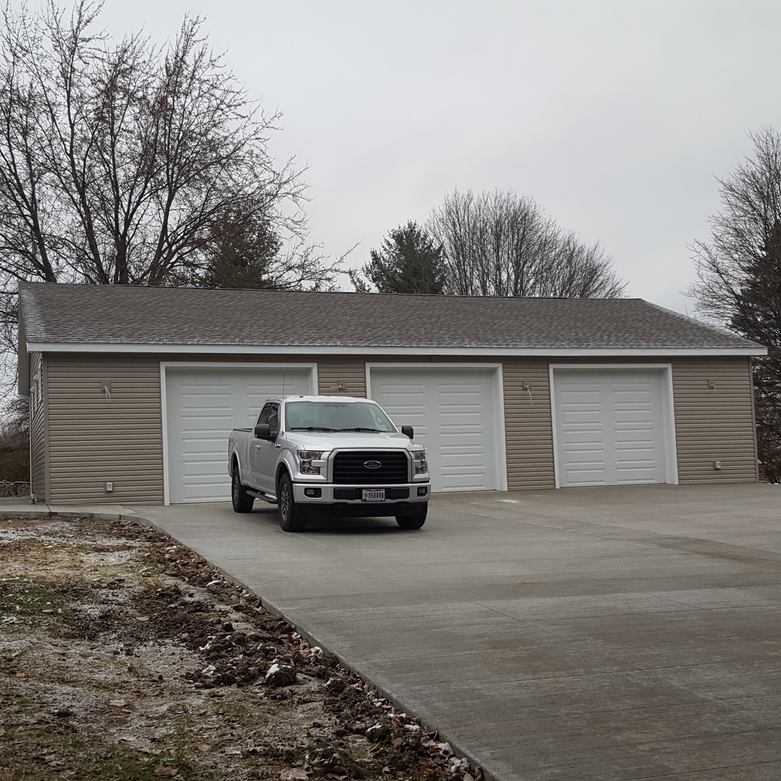 Completed three-bay barndominium with white garage doors built by Lou Reynolds Construction