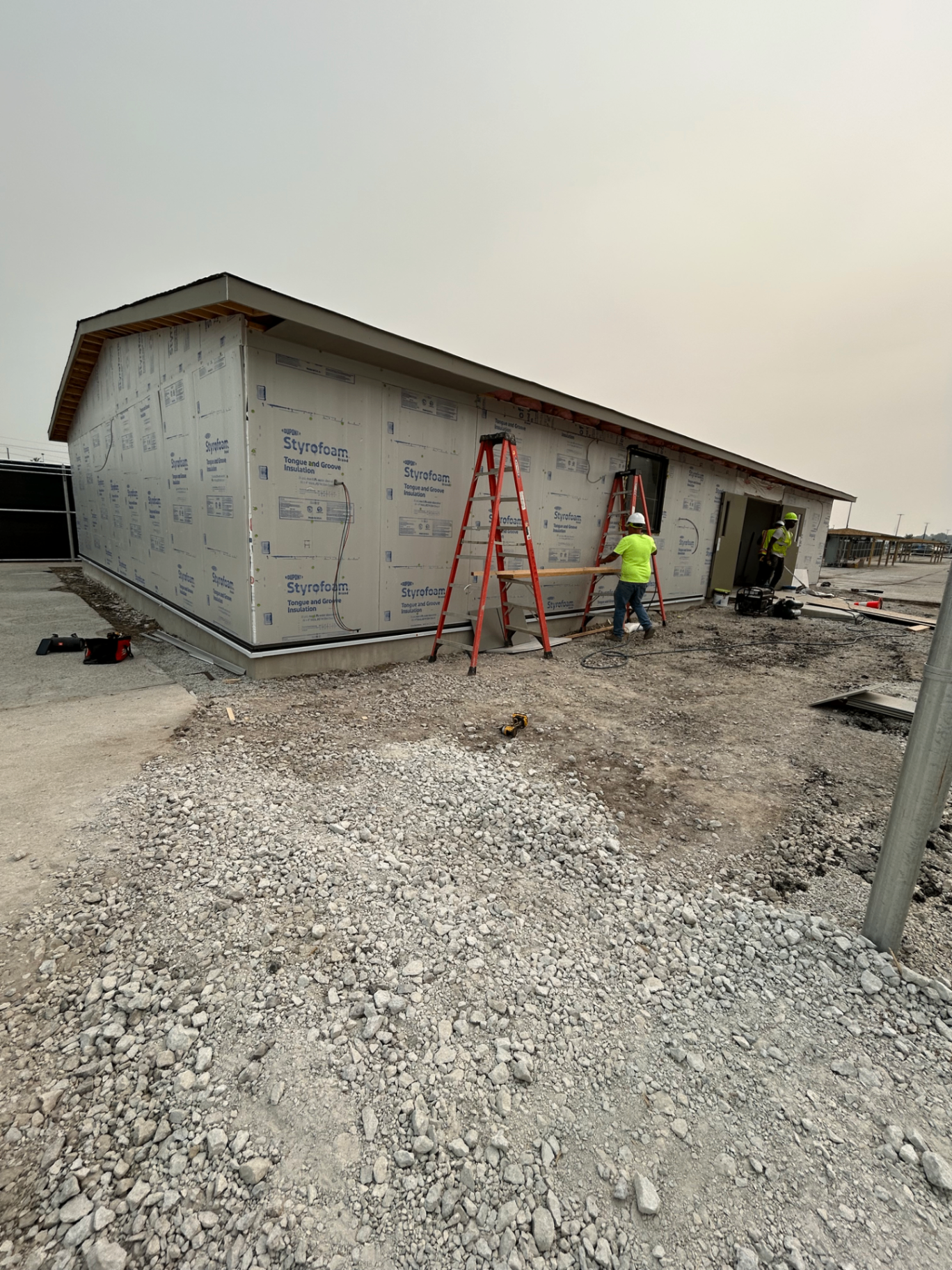 Commercial building mid-construction with insulation and framing crew on site