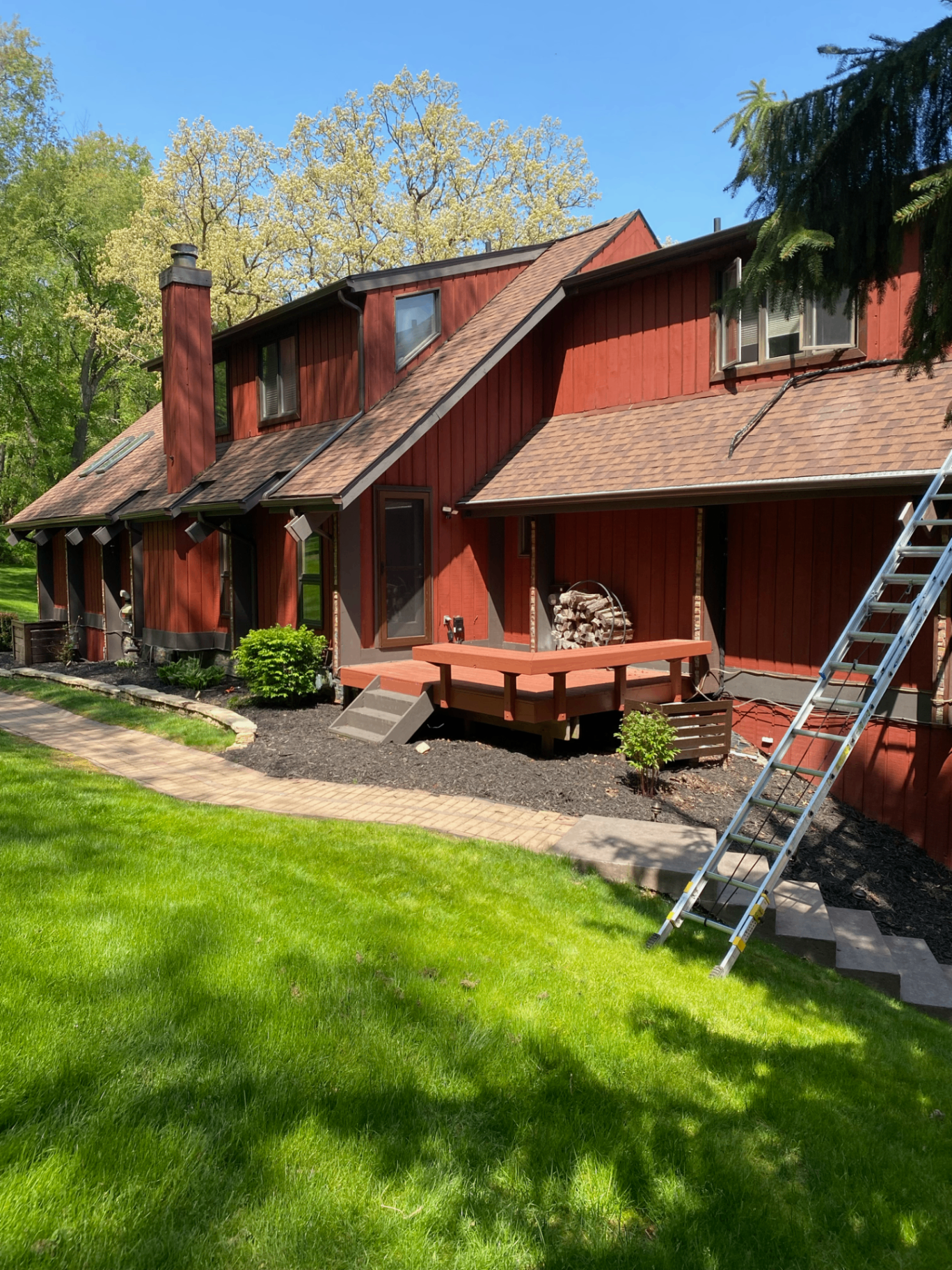 Red board-and-batten home with new shingle roof and gutters