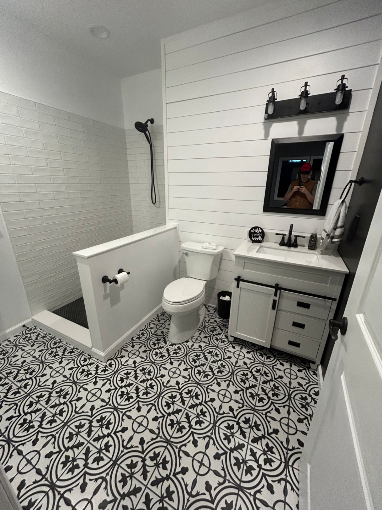 Remodeled bathroom with shiplap walls, patterned tile floor, and modern vanity